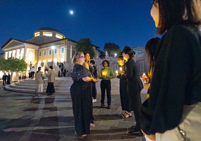 Peace Gala attendees stand outside Founders Hall at dusk.