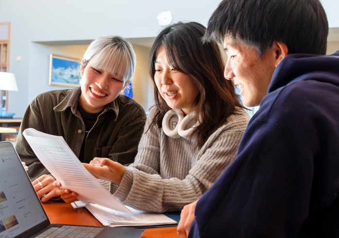 Three Social and Behavioral Sciences students look over a document together.