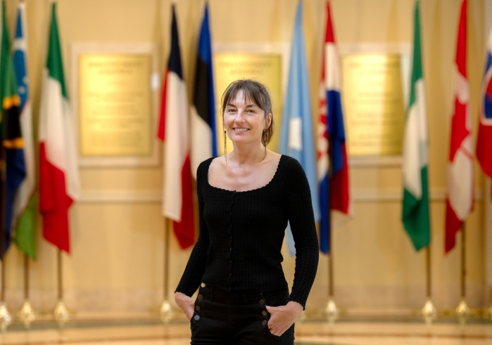 Sandrine Siméon, associate professor of French language and culture and director of the Language and Culture program stands in front of various countries' flags in Founders Hall.