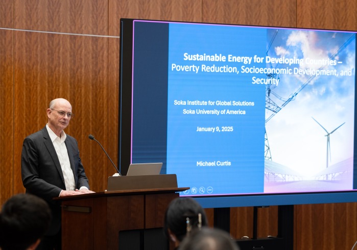 Dr. Michael Curtis stands at the podium beside his presentation during his Jan. 9 talk to the SUA community.
