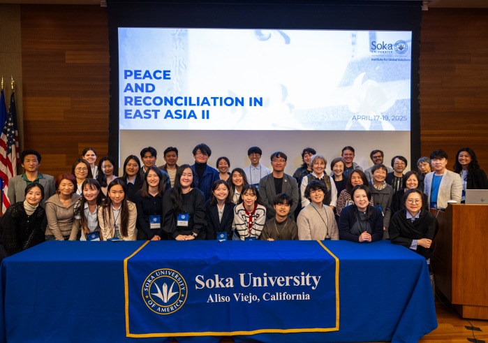 Participants of the 2025 Peace and Reconciliation in East Asia project symposium gather for a group photo in front of a Soka University banner.
