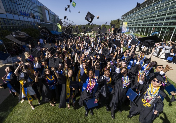 SUA's Class of 2025 smile and throw their caps in the air after commencement.