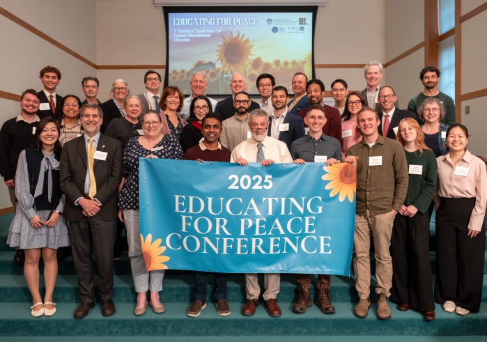 Participants of "Educating for Peace: A Teachers’ Conference for Nuclear Disarmament Education" gather for a group photo holding up a banner stating "Educating for Peace Conference"