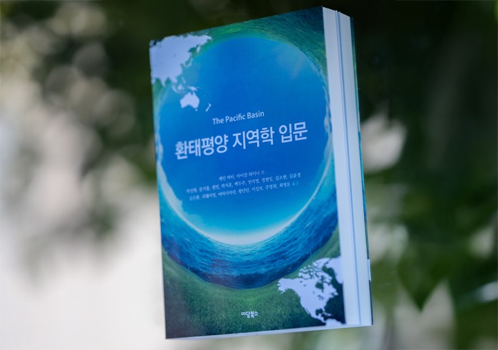 The textbook, “The Pacific Basin: An Introduction" is photographed in front of a white and green bokeh background.