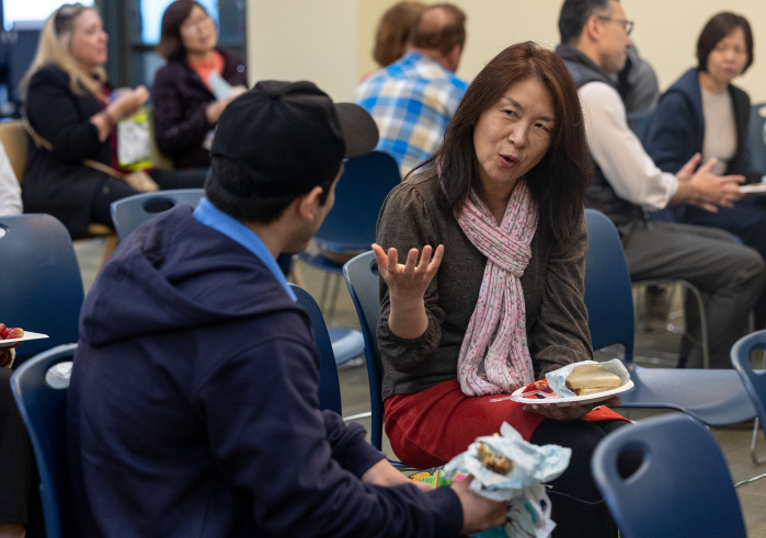 A woman is sitting and talking to a man during the lunch time event