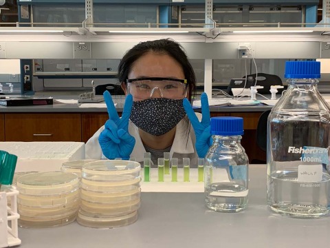 Woman flashing peace sign in bio lab