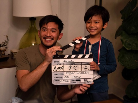 Michael Sasaki poses with a young male actor holding a clapperboard.
