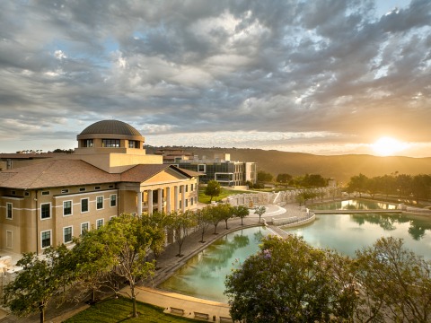 Aerial view of Founders Hall and Peace Lake with clouds and the sun on the horizon