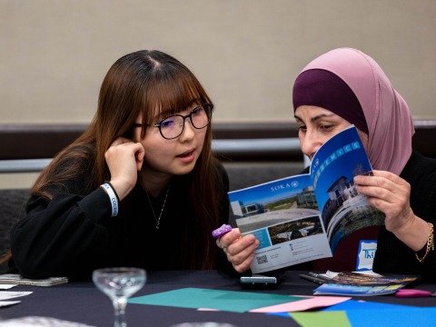 Two women look at a Soka brochure