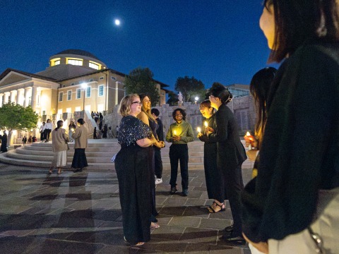 Peace Gala attendees stand outside Founders Hall at dusk.
