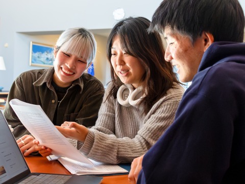 Three Social and Behavioral Sciences students look over a document together.