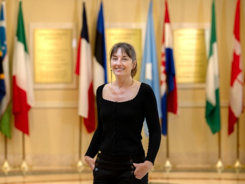Sandrine Siméon, associate professor of French language and culture and director of the Language and Culture program stands in front of various countries' flags in Founders Hall.