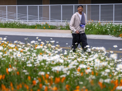 Lucas Colombo ’27 smiles at the camera as he walks among flowers on SUA's campus during the annual Heart of a Lion walk/run.