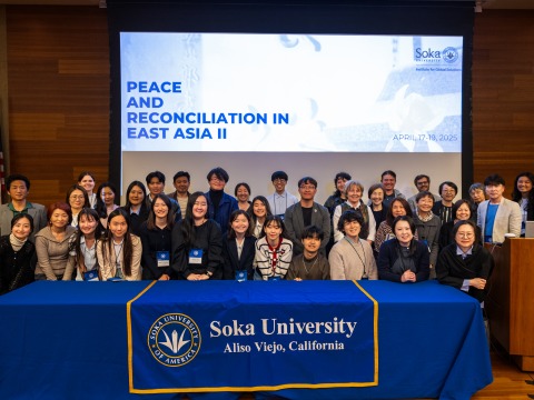 Participants of the 2025 Peace and Reconciliation in East Asia project symposium gather for a group photo in front of a Soka University banner.