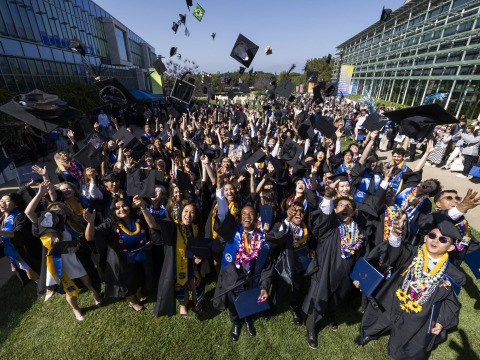 SUA's Class of 2025 smile and throw their caps in the air after commencement.