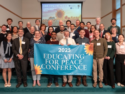 Participants of "Educating for Peace: A Teachers’ Conference for Nuclear Disarmament Education" gather for a group photo holding up a banner stating "Educating for Peace Conference"
