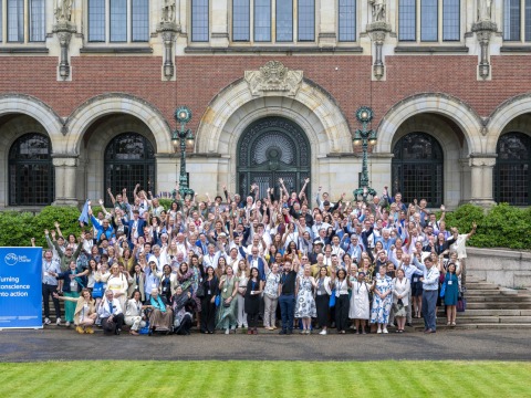 340 participants raise their arms and pose for a group photo during the 25th anniversary of Earth Charter event.