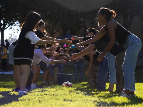 Two lines of people participate in a water-balloon toss during the Welcome Back event on SUA's campus.