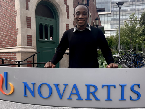 Edem Wordi ’27 poses behind a Novartis sign outside a brick building.