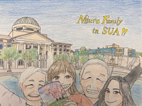 Colored pencil cartoon drawing of a family of four standing in front of Founders Hall and Peace Lake. They are smiling and holding up a children's book. "Miura Family in SUA!!" is stenciled in yellow writing in the top right of the drawing.