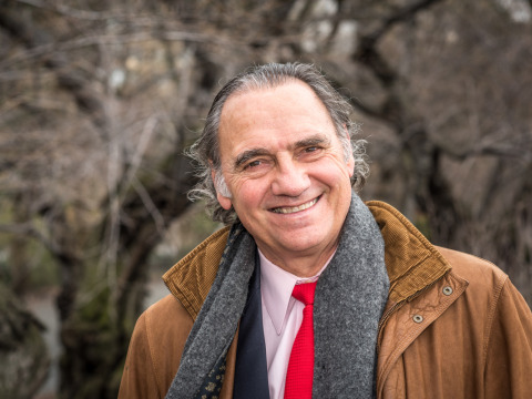 Carlos Alberto Torres smiles in Central Park wearing a grey scarf, brown corduroy jacket, with a light pink collared shirt and red tie.