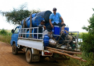 A picture of Michael Schaefer on a truck bed with multiple water barrels. 