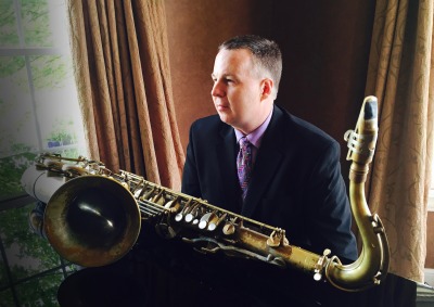 Harry Allen sitting an piano with saxophone