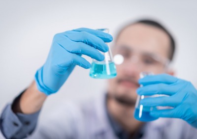 Person holding glass flasks in a lab