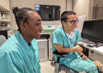 Two students wearing teal scrubs review imaging during their neurosurgery preceptorship in Summer 2023.