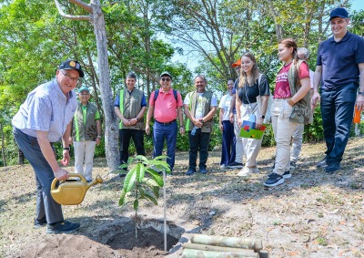 SUA President Ed Feasel waters a plant at the Soka Amazon Institute while a group of people look on