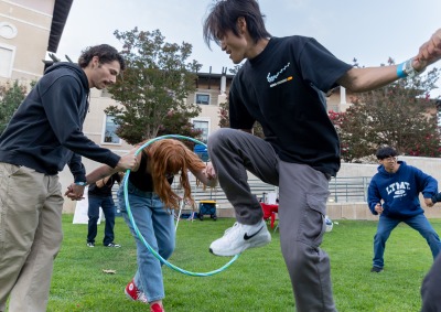 Students hold hands and try to move a hula hoop through a line of people as part of SUA's annual Welcome Back Community Event