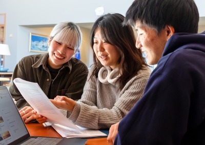 Three Social and Behavioral Sciences students look over a document together.