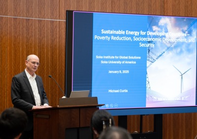 Dr. Michael Curtis stands at the podium beside his presentation during his Jan. 9 talk to the SUA community.