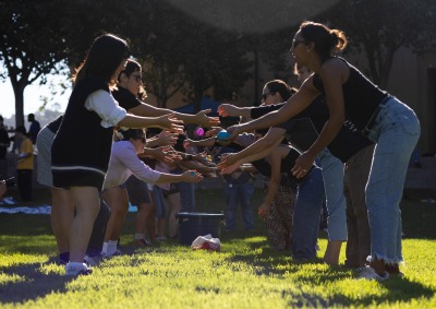 Two lines of people participate in a water-balloon toss during the Welcome Back event on SUA's campus.