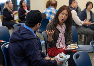 A woman is sitting and talking to a man during the lunch time event