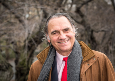 Carlos Alberto Torres smiles in Central Park wearing a grey scarf, brown corduroy jacket, with a light pink collared shirt and red tie. 