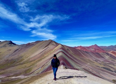 Delali standing in front of Spring Rainbow Mountain in Ecuador