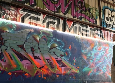 Soka University student looking up at wall of graffiti