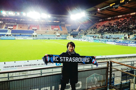 Student in front of football green with Strasbourg banner