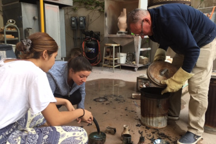 Image of students working with the ceramics instructor.