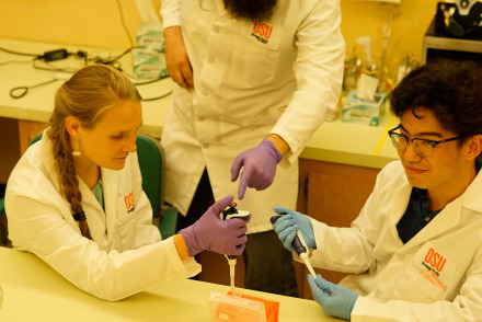 Two students with a professor in a lab. 