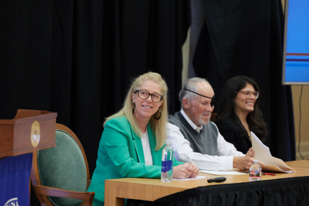 Three panelists sit at a desk together during the SBS Symposium