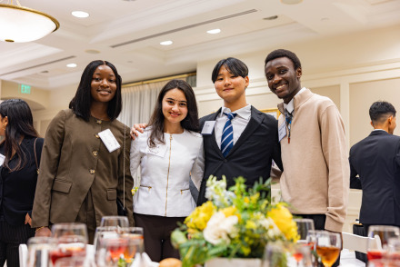 Four formally dressed students pose during an etiquette training event.