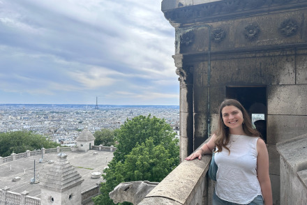 A girl poses at an overlook with the Eiffel Tower in the distance