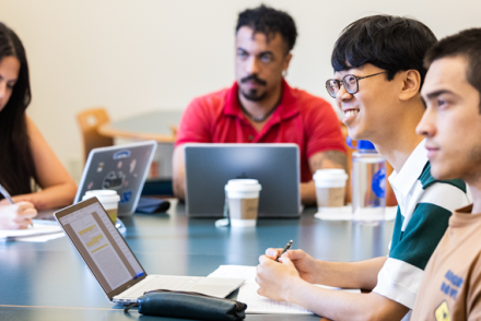 Four graduate students listen to their professor during a class.