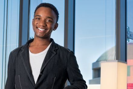 Muchindu Mwanayanda poses in front of glass windows in Curie Hall