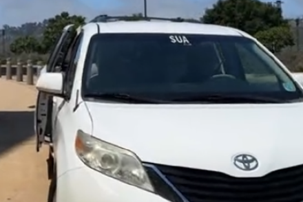 A white van with SUA in white letters is on the top of the windshield is parked on SUA's campus.