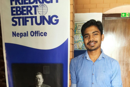 A male student standing next to a company standee 