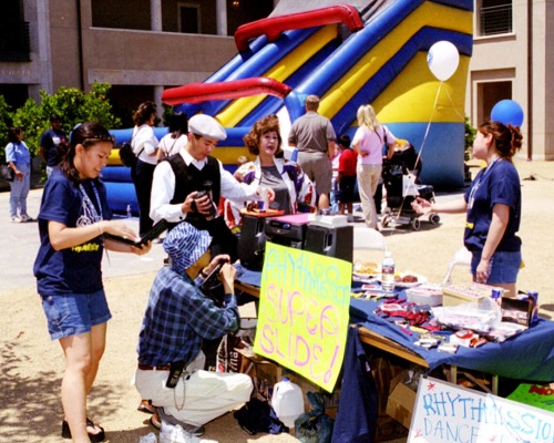 People gather at International Festival booth with inflatable slide in the background