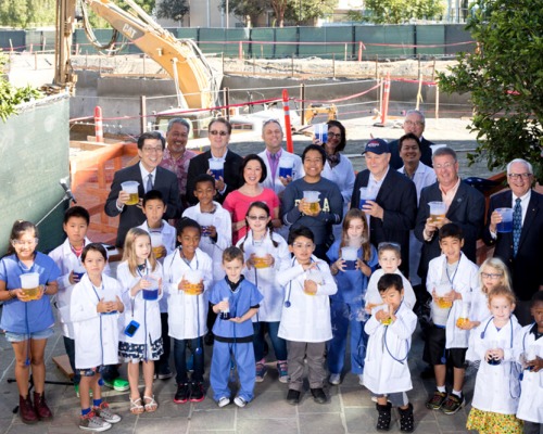 Group shot of dignitaries and young children dressed in medical and lab coats 